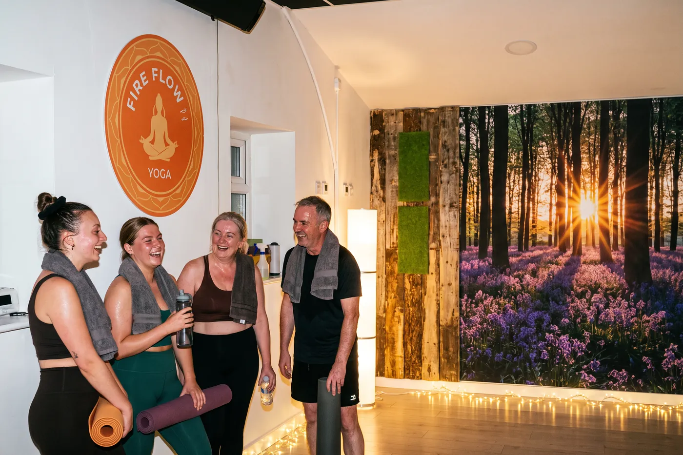 Four students laughing after class beside the Fire Flow sign, towels round their necks